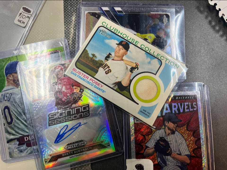 Display of rocks and minerals on tiered wooden stands inside a glass case, featuring amethyst clusters, rose quartz, geodes, fossils, and crystal specimens, some mounted on decorative stands, with handwritten information cards visible.